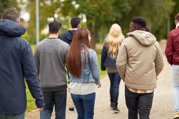 people, friendship, communication and international concept - group of happy friends walking along autumn park