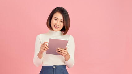 Young beautiful woman using smartphone gadget ipad.Lifestyle concept. Isolated on pink background. - Powered by Adobe