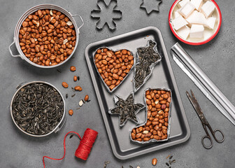 Making birdseeds cookies. All of cookie cutters filled with peanuts and sunflowers seeds. Children education concept. Help people to animals. Top view. 