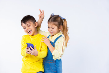 Pastime and children's emotions on white. Children take selfies on a smartphone and put horns on.