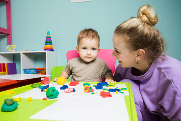 Mom with her baby are having fun studying in the playroom