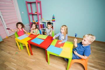 Children show scissors and get ready to cut colored cardboard