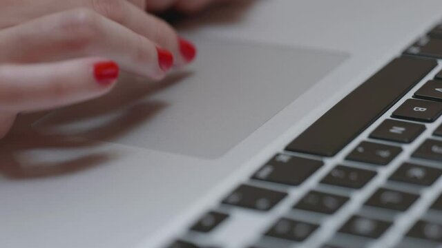 Une femme avec du vernis &agrave; ongle rouge utilise son ordinateur portable