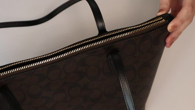 Closeup of Young womans hand opens her bag. Girl opens zip lock on bag
