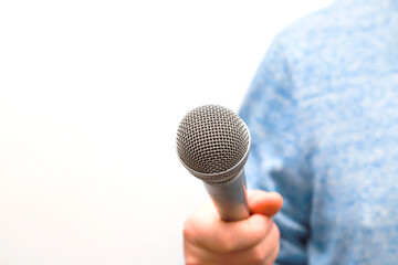 A man holds a silver, gray microphone in his hand and conducts business interviews, journalistic...