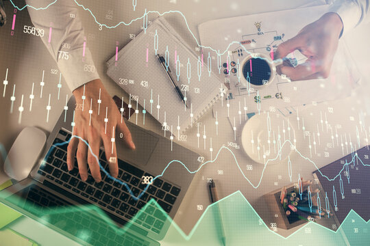 Multi exposure of man's hands typing over computer keyboard and forex graph hologram drawing. Top view. Financial markets concept. © peshkova