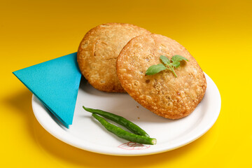 Kachori, green chilly and onion slice in plate. kachori is a spicy snack from India also spelled as kachauri and kachodi.