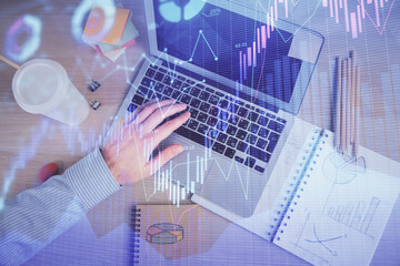 Double exposure of man's hands typing over computer keyboard and forex graph hologram drawing. Top view. Financial markets concept.