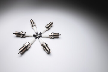 Six new ICE spark plugs on a gray background in contrasting light