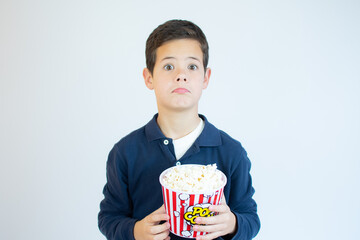 Surprised boy eating pop corn over white background.