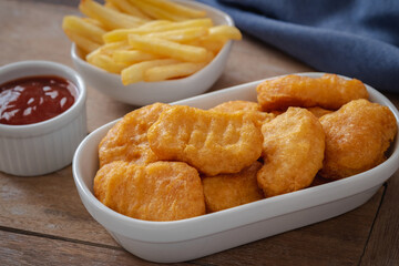 Crispy chicken nuggets and french fries in bowl.