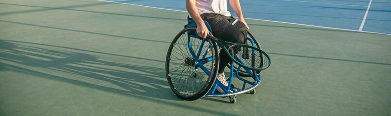 Young man in wheelchair playing tennis on court. disabled tennis player hits the ball during a match outdoor
