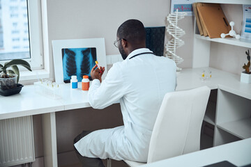 Medical man leaning over a test-glass of vaccine