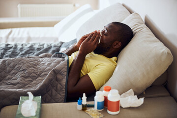 Sick person blowing his nose lying in bed