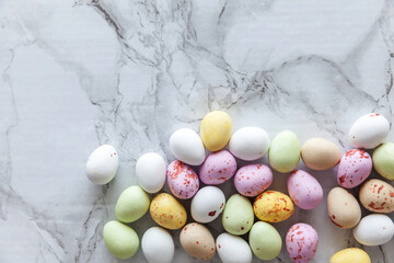 Fototapeta na wymiar Happy Easter concept. Preparation for holiday. Easter pastel candy chocolate eggs sweets on trendy gray marble background. Simple minimalism flat lay top view copy space.