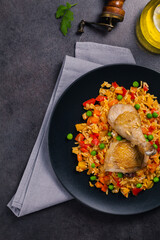 Arroz con pollo. Baked pieces of chicken with bone, rice with paprika and peas.