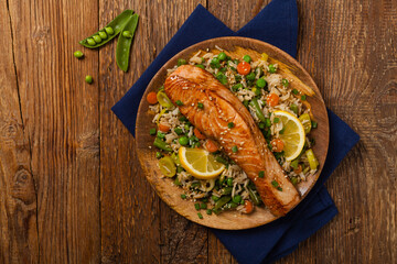 Asian dish. Fried salmon with rice and vegetables. Sprinkled with sesame seeds.