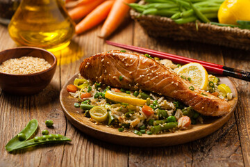Asian dish. Fried salmon with rice and vegetables. Sprinkled with sesame seeds.