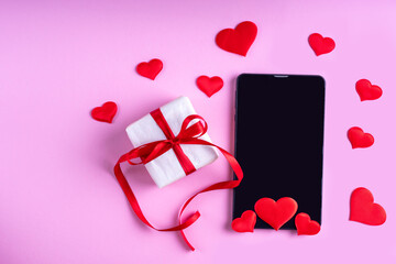 Online congratulations concept. Black blank tablet or phone screen with red hearts shape and gift...