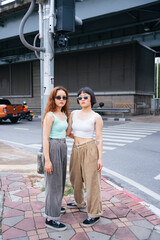 Fashion portrait of two asian women wearing sunglasses on street in city.