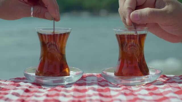 Drinking tea with glass of traditional Turkish tea on the beach. Slow motion video