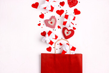 Red shopping bag with gifts and hearts on white background.