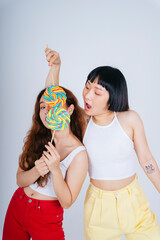 Asian women wearing white vest holding rainbow candy lollipop isolate on white background.