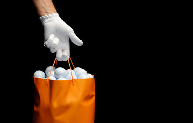 Player wearing a golf glove holding a bag full of golf balls.