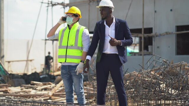 asian foreman and african american architect  checking steel structure outdoors on construction site at village . contractor worker Inspection and correction rebar steel cage . quality control