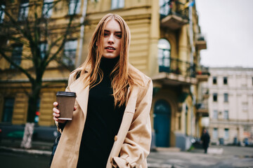 Calm female in trendy coat standing on street