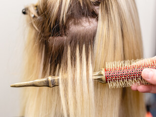 Blonde hair extensions procedure in beauty salon