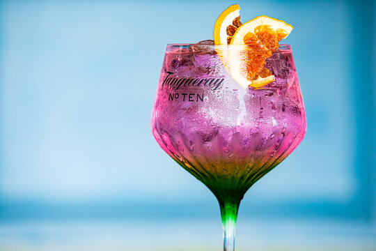 Cape Town, South Africa - December 14, 2020: Illustrative Editorial of Tanqueray Gin branded cocktail glass containing a pink carbonated soda drink