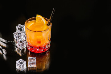 Orange aperol cocktail with ice on dark background
