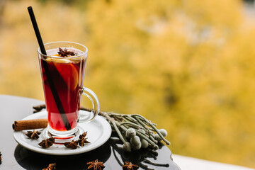 Aromatic mulled wine in glass on autumn background