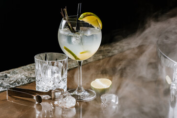 Obraz premium Transparent alcohol cocktail with lime and ice on the smoky background