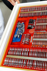 Naklejka premium Opthalmology test box. The universal-messbrille tool of the optometrists and oculists. Set of dioptric glasses. Eyesight correction. Female hand holds dioptric lenses.