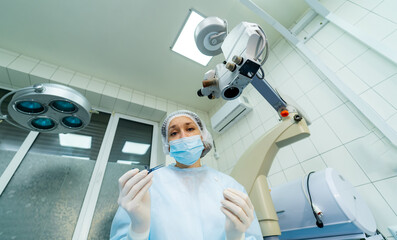 Surgeon is working in operating room from the eyes of a patient. Hospital background. Female doctor...