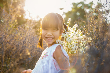Portrait of young fun happy little cute asian girl playing in meadow flower field in spring or summer season. Education for toddler or preschool, childhood healthy lifestyle nature concept