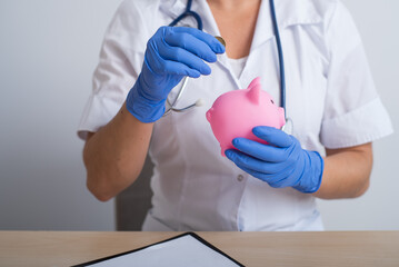 A faceless female doctor puts a coin in a piggy bank