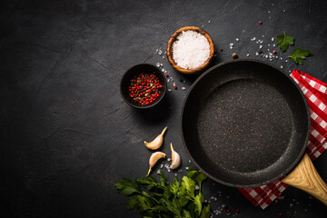 Food cooking background with Frying pan or skillet, spices and herbs on black stone table. Top view...