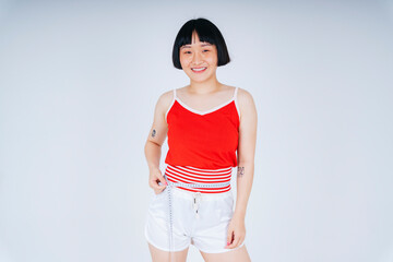 Portrait of asian short bob hairstyle wearing red shirt using measure tape on her waist.