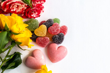 top view of heart shaped candies and flowers, flat lay of berry sweets or marmalade and roses for valentine's day, wedding or anniversary; romantic card with copy space