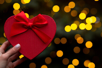Woman holding a heart shaped red box on a bokeh background