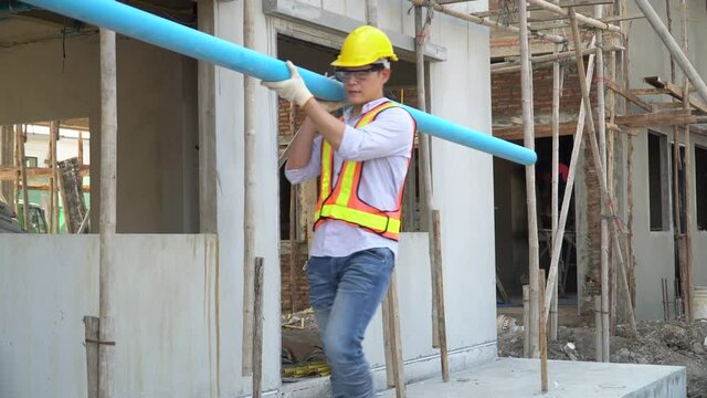 asian construction worker carrying water pvc pipe working in construction site