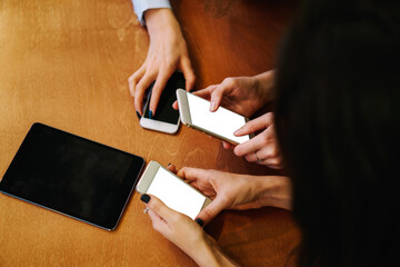Obraz premium Unrecognizable women messaging via smartphones near modern tablet