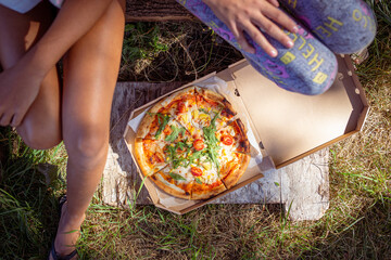 Two teenage girls sitting outdoor with pizza