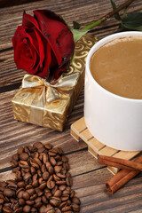 Top view of heart shaped coffee beans and white coffee mug against wooden background. Coffee lovers. 