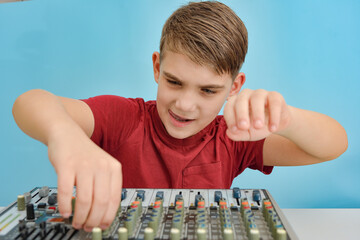 A young DJ is adjusting the equalizer on a music mixing console.