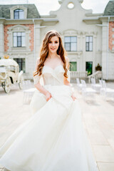 Obraz premium cheerful beautiful woman in white wedding dress whirls near beautiful building.