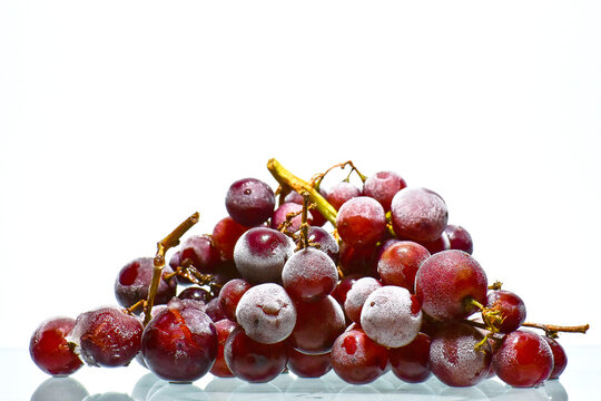 Close-up Of Frozen Red Grapes Against White Background